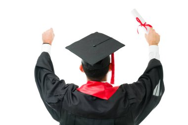 Mezuniyet töreninde üniversite sertifikası aldıktan sonra kollarını havaya kaldıran önlüklü ve şapkalı genç bir erkek mezunun arka görünüşü.