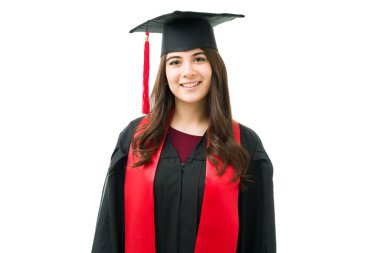 Mezuniyet fotoğrafı ve seremonisi için gülümseyen çekici beyaz kadın. 20 'li yaşlarda, siyah bir elbise, kep ve kırmızı püsküllü bir kadın.