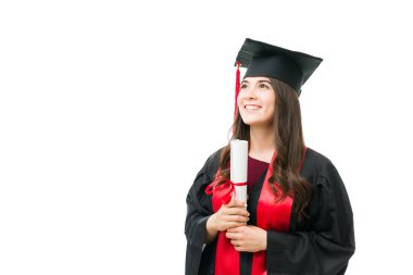 Üniversite diplomasını iki eliyle tutan ve mezuniyet töreninde gururlu ve minnettar hisseden çekici genç bir bayan mezun.