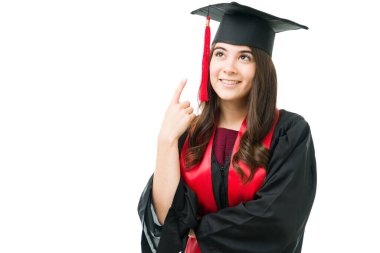 Mezuniyet şapkasına bakıp işaret eden çekici genç bir kadın. Mutlu bayan mezun. Üniversite diplomasını almaktan mutlu ve gururlu.