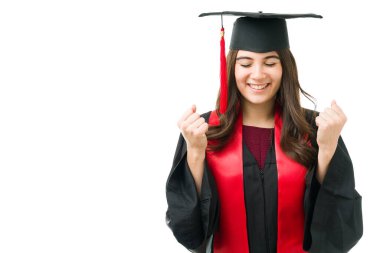 Gözleri kapalı gülümseyen ve akademik başarısını kutlayan çekici genç bir kadın. Mezuniyet elbisesi giymiş bir kız öğrenci üniversite diplomasını aldığına inanamıyorum.