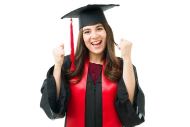 Güzel beyaz bir kadın, lisans diplomasını aldığı için heyecanlanıyor. Mezuniyet töreninde elbisesiyle heyecanla bağıran bir bayan mezun.