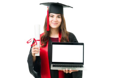 Kolej diplomasını ve dizüstü bilgisayarını tutan beyaz bir kadının portresi. Sanal mezuniyet töreninde kadın mezun sertifikayı aldı 