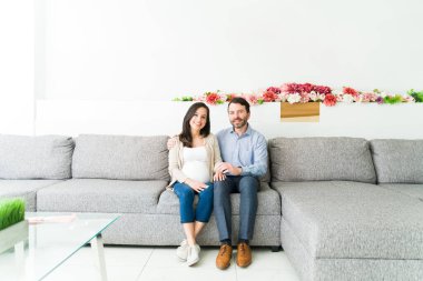 Güzel bir çift rutin bir muayene için doktorun muayenehanesinde beklerken sarılıyor. Hamile kadın ve kocası doktor randevularını bekliyorlar.