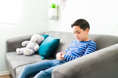 Üzgün ilkokul çocuğu kötü davranışları yüzünden terapistinin koltuğunda tek başına oturuyor. Çocuk terapisi seansında depresyona girmiş küçük bir çocuk.