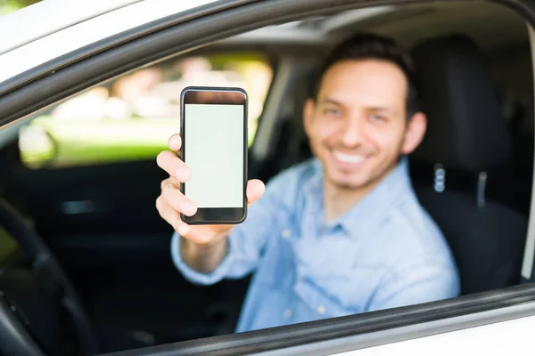 Attractive man showing the screen of his smartphone while sitting on the driver\'s seat of his car. Male taxi driver using a transportation mobile app