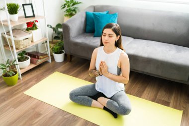 Woman in her 20s doing a praying yoga pose with her eyes closed. Good-looking woman exercising and relaxing to keep a positive mental health