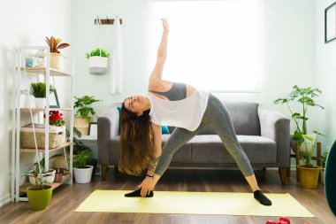 Oturma odasında spor yapan aktif genç bir kadın. Evde yoga yaparken gülümseyen mutlu kadın. 
