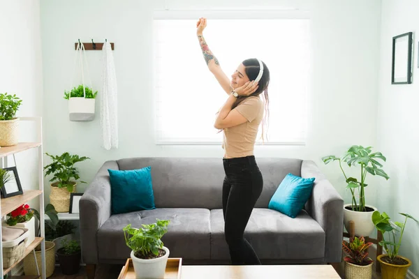 Attractive woman dancing while feeling happy and free during a relaxed day at home. Latin woman listening to music and her favorite song with headphones