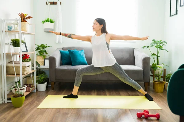 Beautiful young woman focused on health and wellness doing a yoga workout routine in her living room to keep a positive mental health