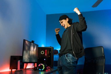 Çekici genç bir adam oyun bilgisayarıyla masasının önünde dururken tezahürat ve çığlık atıyor. Erkek oyuncu çevrimiçi bir video oyunu kazanıyor