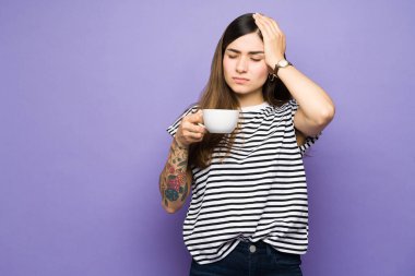 Latin genç bir kadın henüz kahve içmediği için baş ağrısı çekiyor. Kafein içtikten sonra migreni olan 20 'li yaşlarda bir kadın.