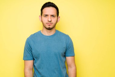 30 'larında öfkeli bir adam parlak bir arka planda dururken göz teması kuruyor. Latin bir adam kavgadan sonra üzgün ve öfkeli hissediyor 