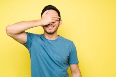 Mutlu ve neşeli adam gülümsüyor ve sürpriz bir hediye bekliyor. Latin yakışıklı adam gözlerini kapatırken heyecanlanıyor ve gülüyor.