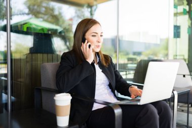 Güzel bir iş kadını, bir müşterisiyle ya da iş arkadaşıyla bilgisayarında yazarken ya da bir kahve dükkanının avlusunda otururken akıllı telefonuyla konuşuyor.