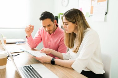 Çekici iş arkadaşları ofiste otururken birlikte çalışıp iş sözleşmesi okuyorlar. Profesyonel ortaklar çalışma kağıtlarını masalarında okuyorlar.