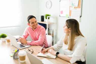 Ofiste otururken iş arkadaşına gülümseyen mutlu bir iş arkadaşı. Güzel bir kadın çekici bir adamla meslekleri hakkında konuşuyor.