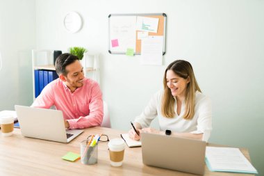 Çekici İspanyol adam ve beyaz güzel kadın ofislerinde oturup gülümserken ve işlerinden bahsederken.