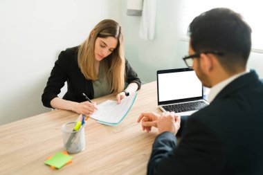 Profesyonel beyaz kadın erkek avukatıyla sözleşme imzalıyor. İş arkadaşı bir iş arkadaşıyla çalışma belgelerini yazıyor ve inceliyor. 