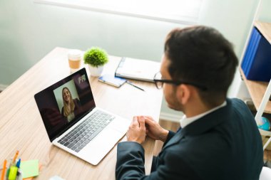 Beyaz bir kadın ve profesyonel bir meslektaşla çevrimiçi bir video görüşmesinde yakışıklı bir İspanyol ve patronun yüksek açısı.