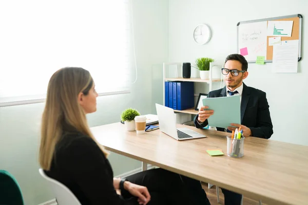 Caucasian young woman sitting with the human resources manager during a job interview. Male boss asking questions to a woman and holding her resume at the office