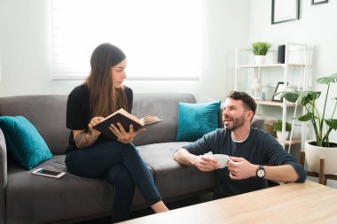 Yakışıklı adam evde bir fincan kahve içerken kız arkadaşıyla gününden bahsediyor. Elinde kitap tutan ve kocasını dinleyen genç bir kadın.