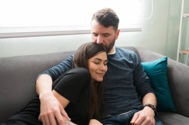 İspanyol koca, sevgili güzel eşinin kafasının tepesini öperken evde bir randevu sırasında kanepede sıkıca sarılıyor.