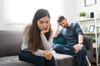 Depresyondaki genç bir kadın hamilelik testinin negatif sonuçlarına bakarken üzgün hissediyor. İspanyol çift hamile kalamıyor.