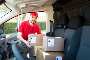 30 'lu yaşlardaki İspanyol bir adam teslimat kamyonundan bir paket çıkarıyor. Mutlu erkek kurye, nakliye adresine varıyor.