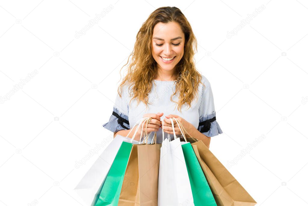 Beautiful young woman smiling while holding her shopping bags and looking down. Hispanic woman in her 20s going shopping at the mall