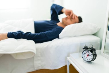 Uykulu genç adam uyukluyor ve alarm sesiyle geç kalkıyor. İspanyol adam sabah uyuyakalmış.