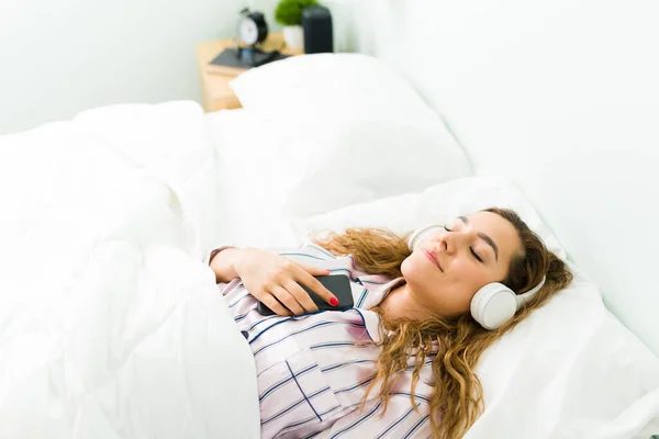 Mujer Relajada Tranquila Descansando Cama Blanca Cálida Pijama Mientras Escucha —  Fotos de Stock