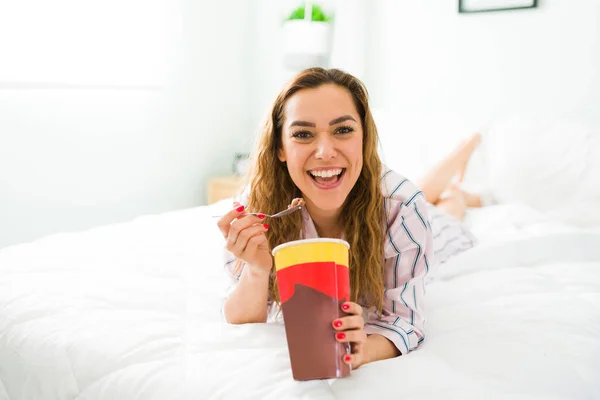 幸せな美しい女性の肖像画彼女の快適なベッドで休んで チョコレートアイスクリームを食べながら笑顔 — ストック写真