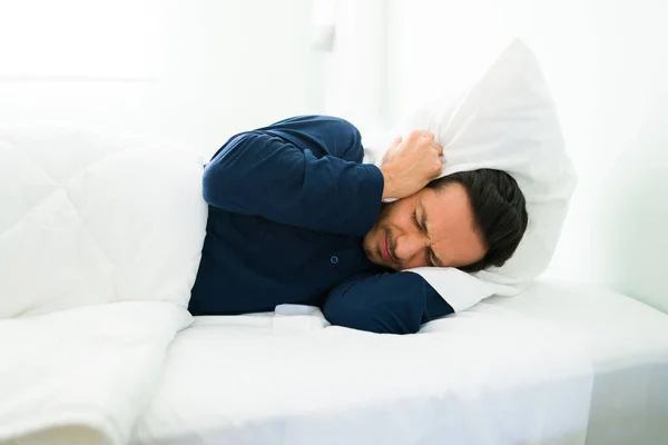 Homem Latino Perturbado Deitado Cama Cobrindo Seus Ouvidos Com Travesseiro — Fotografia de Stock