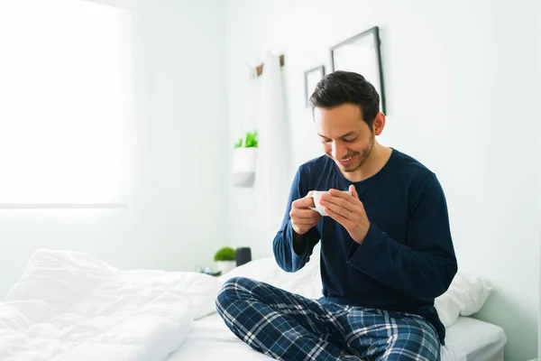 Joven Relajado Pijama Sonriendo Sentado Cama Mientras Bebe Una Taza — Foto de Stock