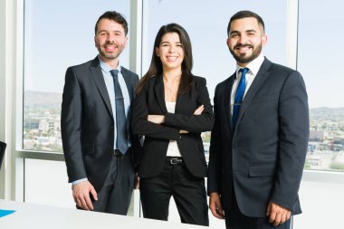 Takım elbiseli çekici yöneticiler iş sunumuna başlamadan önce toplantı odasında dururken gülümsüyor ve göz teması kuruyorlar.