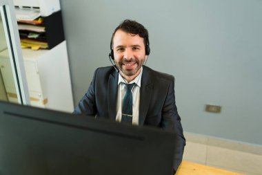 Satış temsilcisi işte mutlu hissediyor. Kulaklığı olan çekici İspanyol bir yönetici. Telefonlara bakıyor ve müşteri hizmetleri sunuyor. 