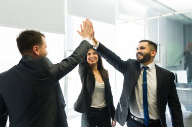 Harika bir takım çalışması. Mutlu iş arkadaşları beşlik çakıyor ve şirkette büyük bir iş anlaşmasını kutluyorlar.