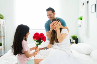 Her şey için teşekkürler anne. Baba ve küçük kız sabah bir buket güzel çiçekle genç bir anneye sürpriz yapıyorlar doğum günü veya anneler günü için.