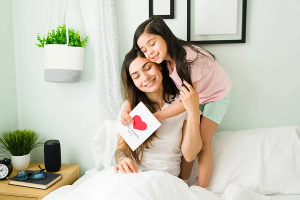 어머니 아름다운 소녀가 침대에서 포옹하고 있습니다 어머니에게 손으로 카드를 — 스톡 사진