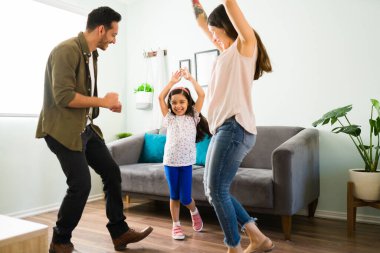 Müzik her şeyi daha iyi yapar. Genç bir aile evde eğleniyor ve ilkokul kızlarıyla dans ediyor.