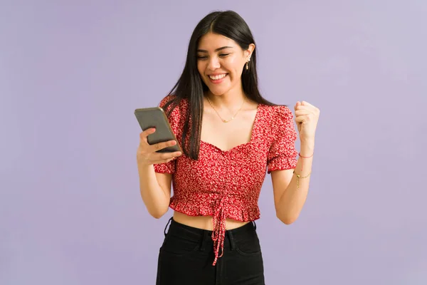 西班牙裔年轻女性在智能手机上收到了一封肯定的短信 并庆祝这个好消息 — 图库照片