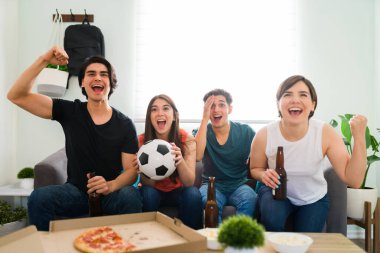 Bir futbol maçı izleyen ve futbol takımı maçı kazandığı için sevinçle bağıran bir grup iyi görünümlü arkadaş.  