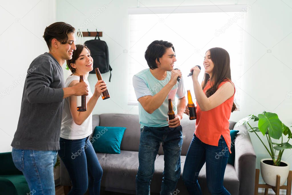 Best friends having a double date at home. Couple of friends singing a karaoke song with a microphone in the living room