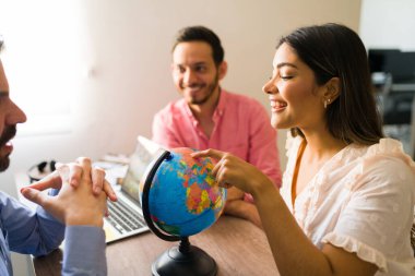 Bu güzel ülkeyi ziyaret etmek istiyorum. Bir seyahat acentesinin yardımıyla tatil tatilini seçen mutlu ve çekici genç bir kadın.
