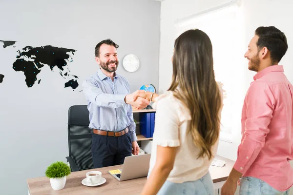 Welcome to my travel agency. Hispanic couple arriving to the office of a sales representative to buy a vacation package