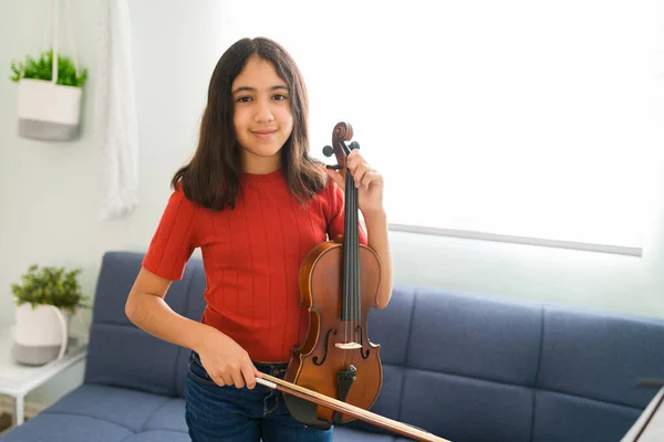 彼女の音楽のために弓でバイオリンを演奏しながら 才能のある創造的な女の子は笑顔と目の接触を作ります自宅で — ストック写真