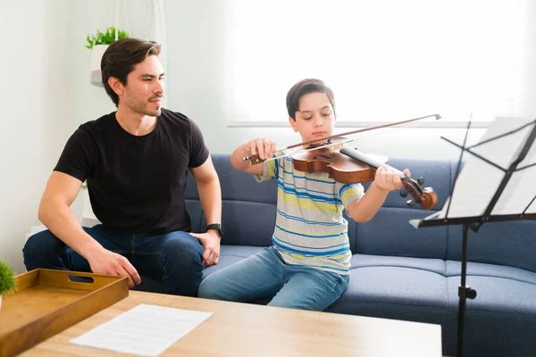 若い男性教師と彼の家の音楽のレッスンの間にシート音楽の一部でバイオリンを演奏熟練した若い男の子 — ストック写真