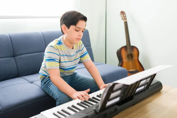 創造的な子供は自宅でピアノを演奏し 彼の音楽レッスンのために練習します 新しい楽器を演奏することを学ぶ芸術少年 — ストック写真