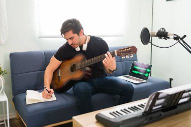 Şarkı yazarken ilham geldi. Akustik gitarlı İspanyol genç bir adam ve müzisyen evde şarkı besteliyor.